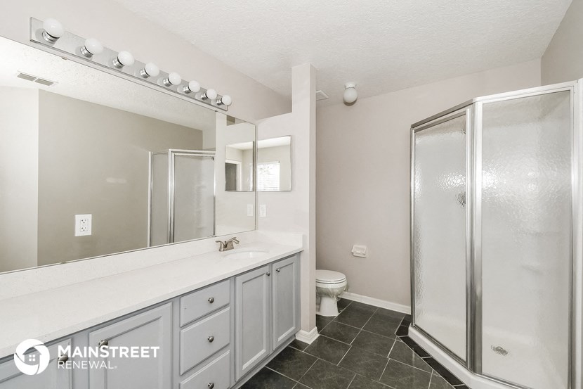 a white bathroom with a large mirror and a shower