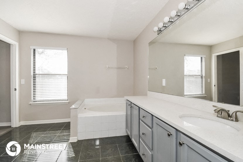 a white bathroom with a tub and a sink and a mirror