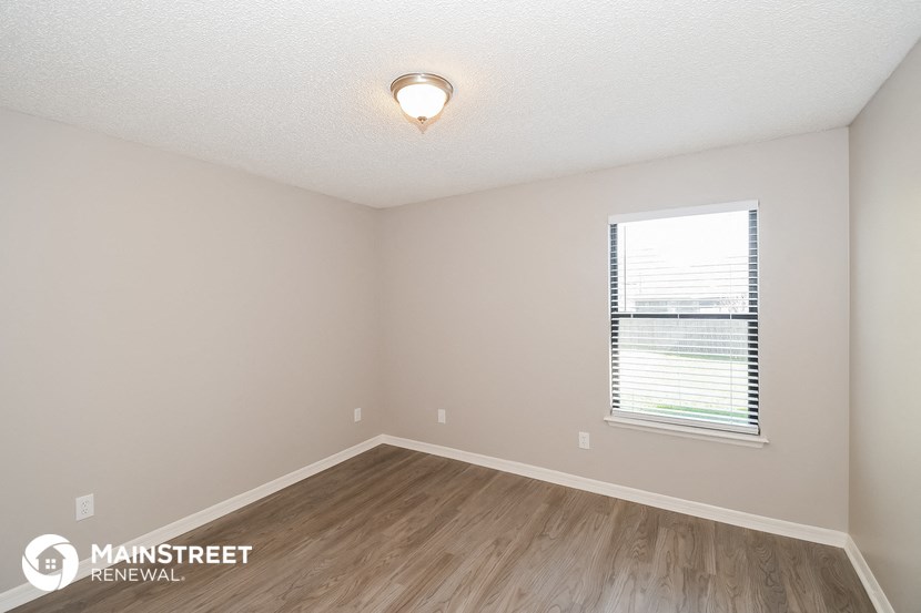 the spacious living room with wood flooring and a window