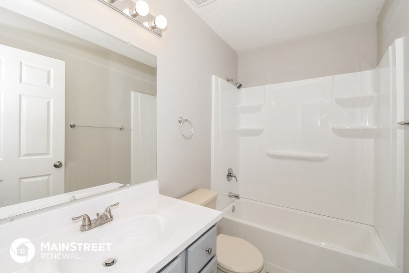 a white bathroom with a tub and a sink and a mirror
