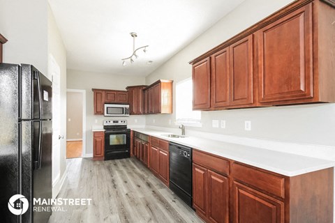 a kitchen with wood cabinets and white counter tops and black appliances