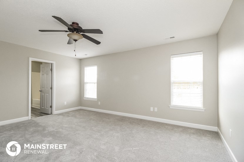 an empty living room with a ceiling fan