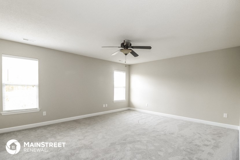 an empty living room with a ceiling fan