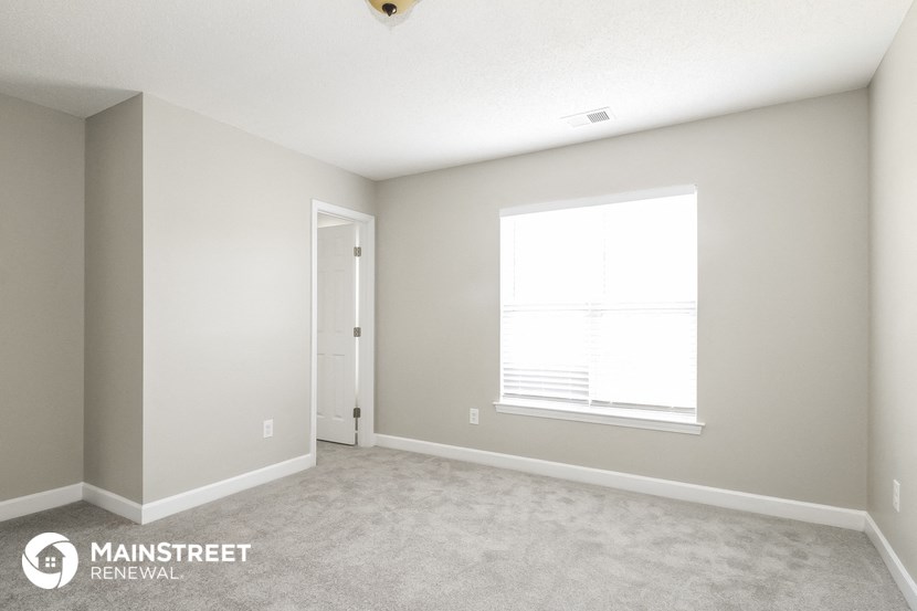 a bedroom with a large window and a carpeted floor
