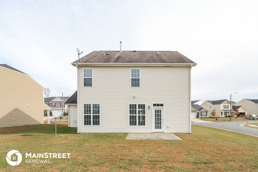 a small white house with a yard in front of a street