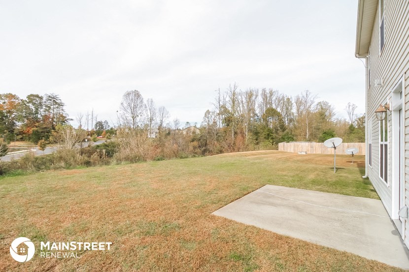 the backyard of a house with a yard and a basketball court