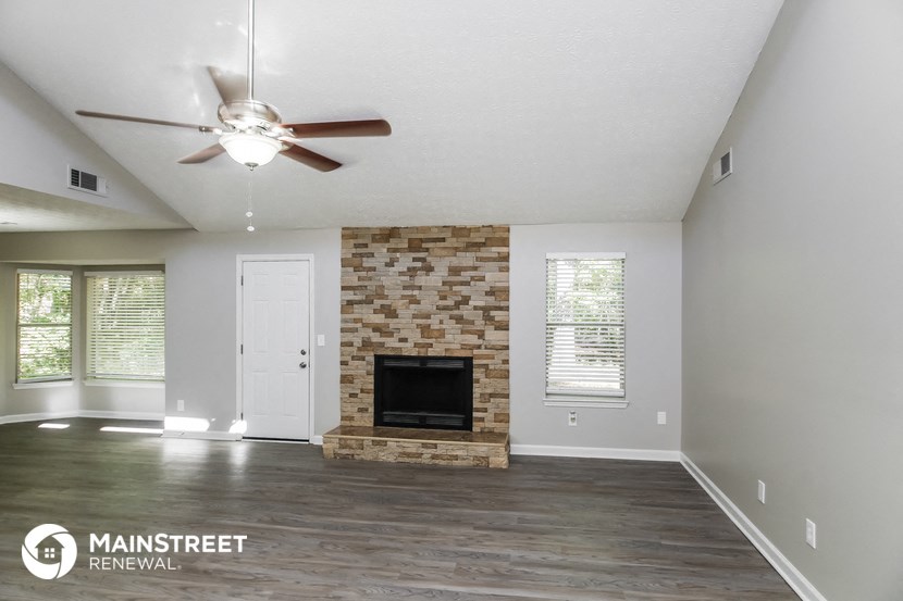 a living room with a fireplace and a ceiling fan