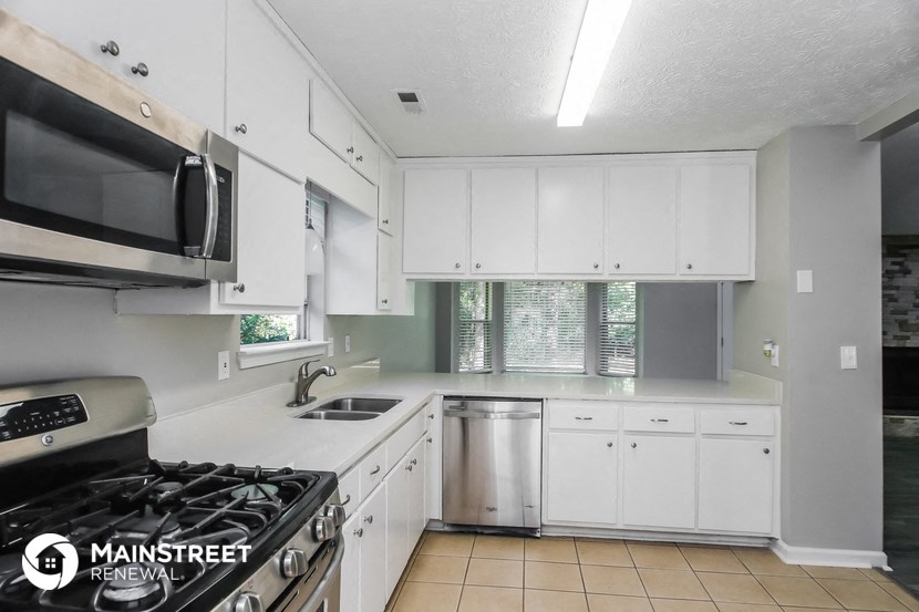 an empty kitchen with white cabinets and stainless steel appliances