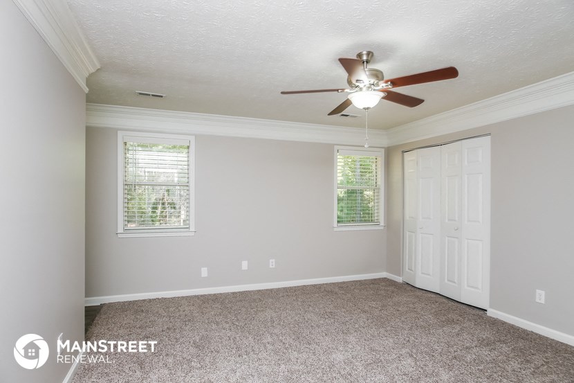 the spacious living room with ceiling fan and carpeting