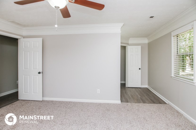 the living room of a renovated house with white walls and a ceiling fan
