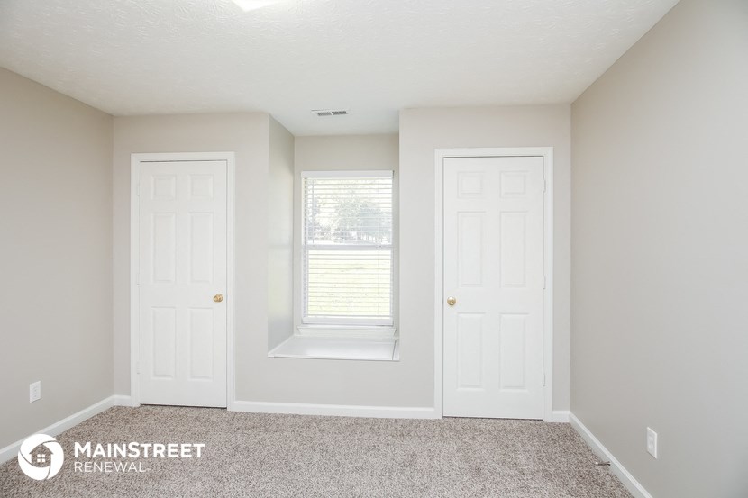 a bedroom with two doors and a window and a carpeted floor