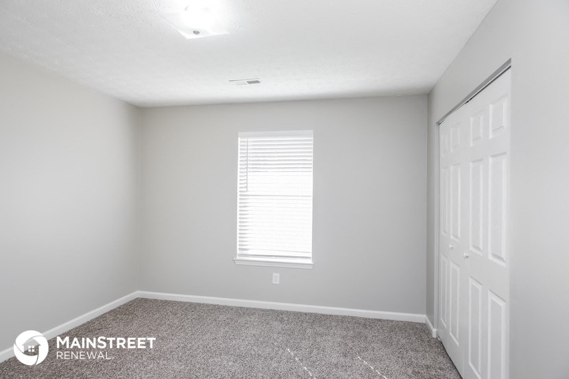 the upstairs bedroom has a large window and carpeted flooring
