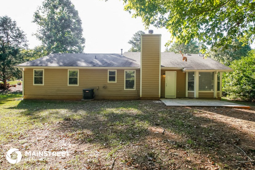 a small yellow house with a yard and some trees