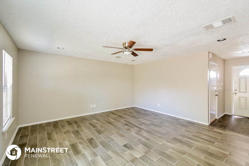 the spacious living room with tile flooring and a ceiling fan