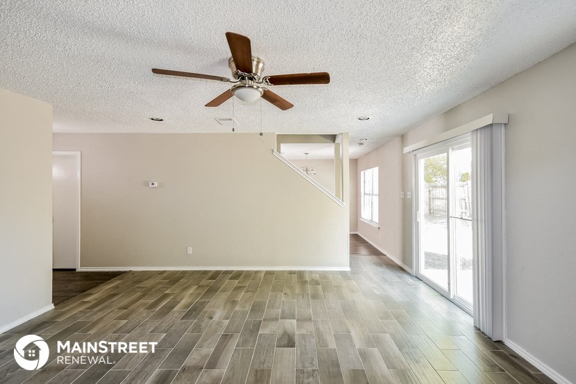 the spacious living room with ceiling fan and wood flooring
