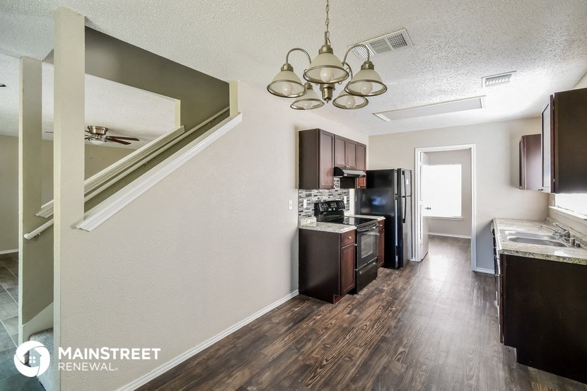 a kitchen with wood flooring and stainless steel appliances and
