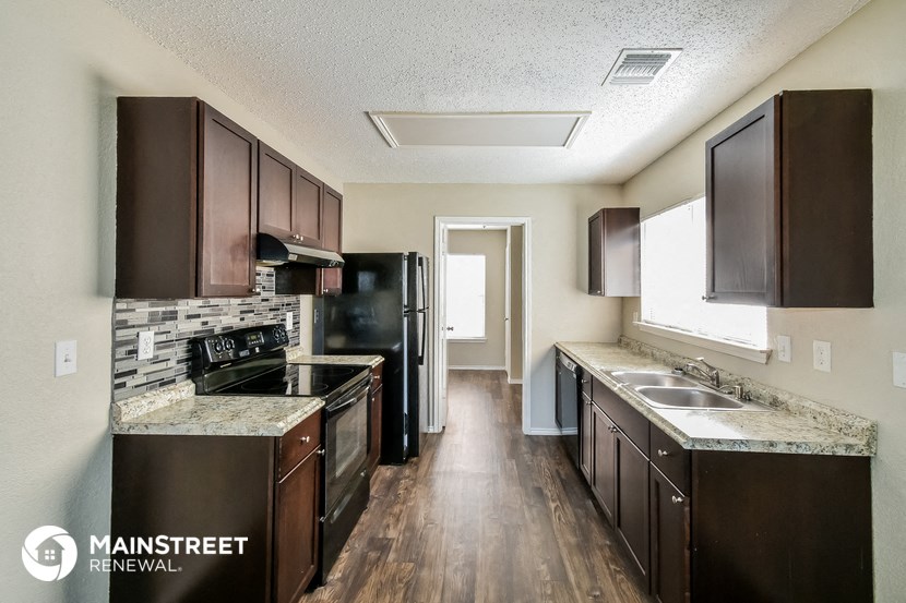 a kitchen with dark wood cabinets and granite counter tops and a black refrigerator