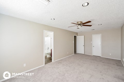 a spacious living room with carpet and a ceiling fan