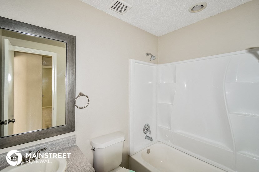 a bathroom with a white tub and a toilet and a mirror