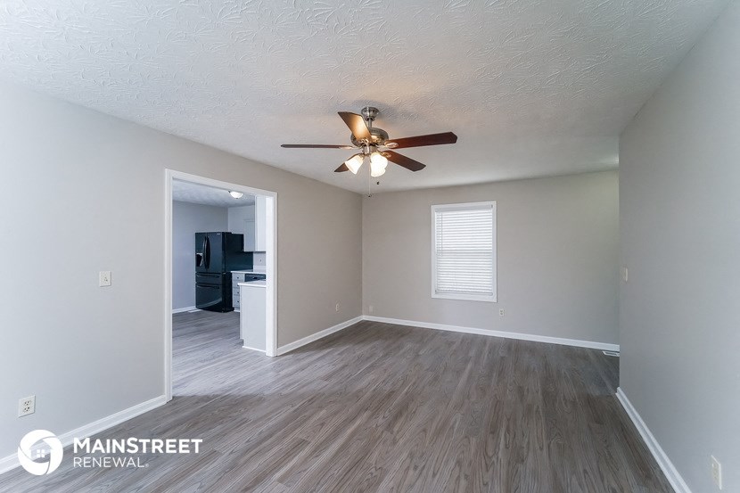 the spacious living room with ceiling fan and wood flooring