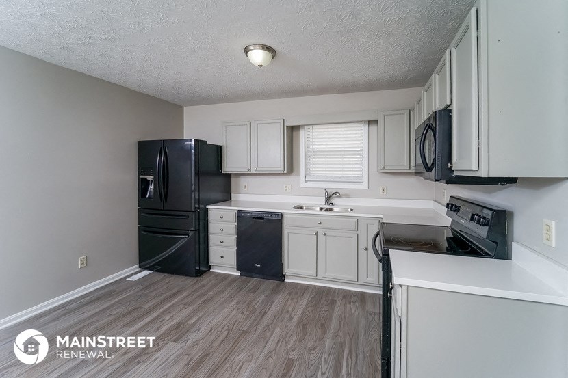 a kitchen with white cabinets and a black refrigerator