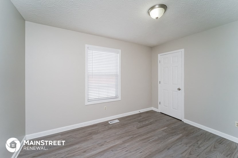 the living room of an apartment with a wood floor and a white door