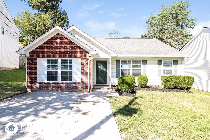 a small white house with a lawn and a driveway