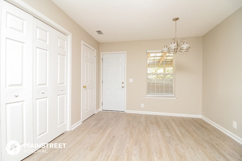 an empty living room with white doors and wood floors