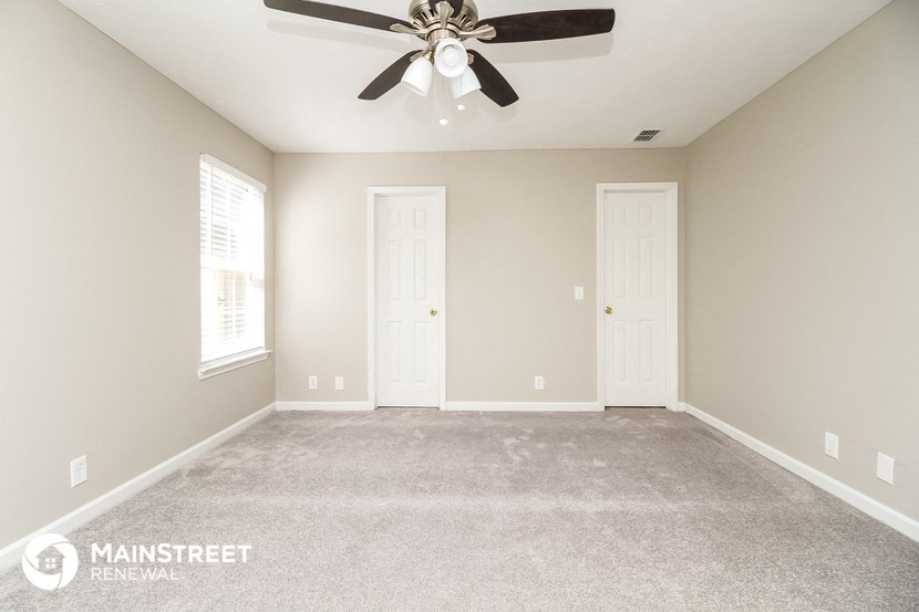 the master bedroom has a carpeted floor and a ceiling fan