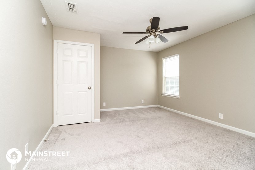 the master bedroom has a carpeted floor and a ceiling fan