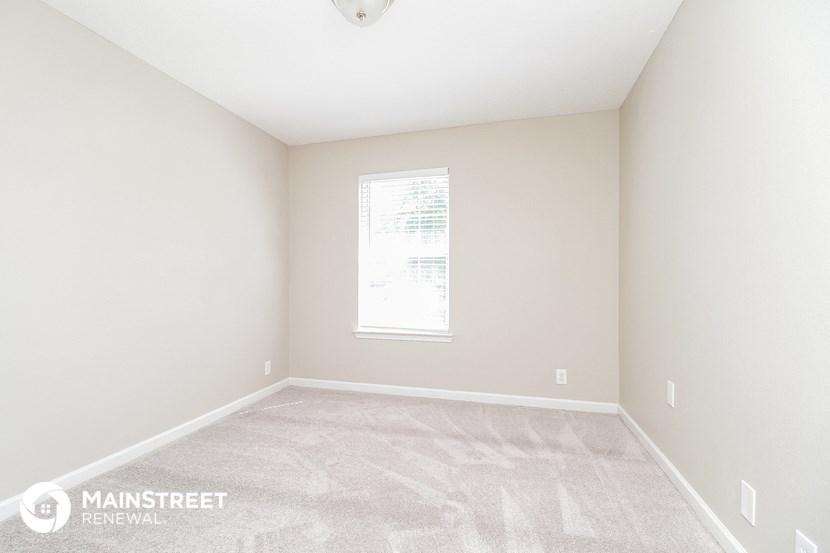 the upstairs bedroom with carpeted flooring and a window