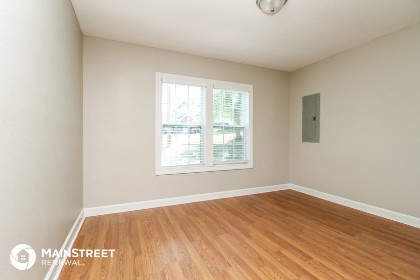 the living room of a home with wood floors and a window