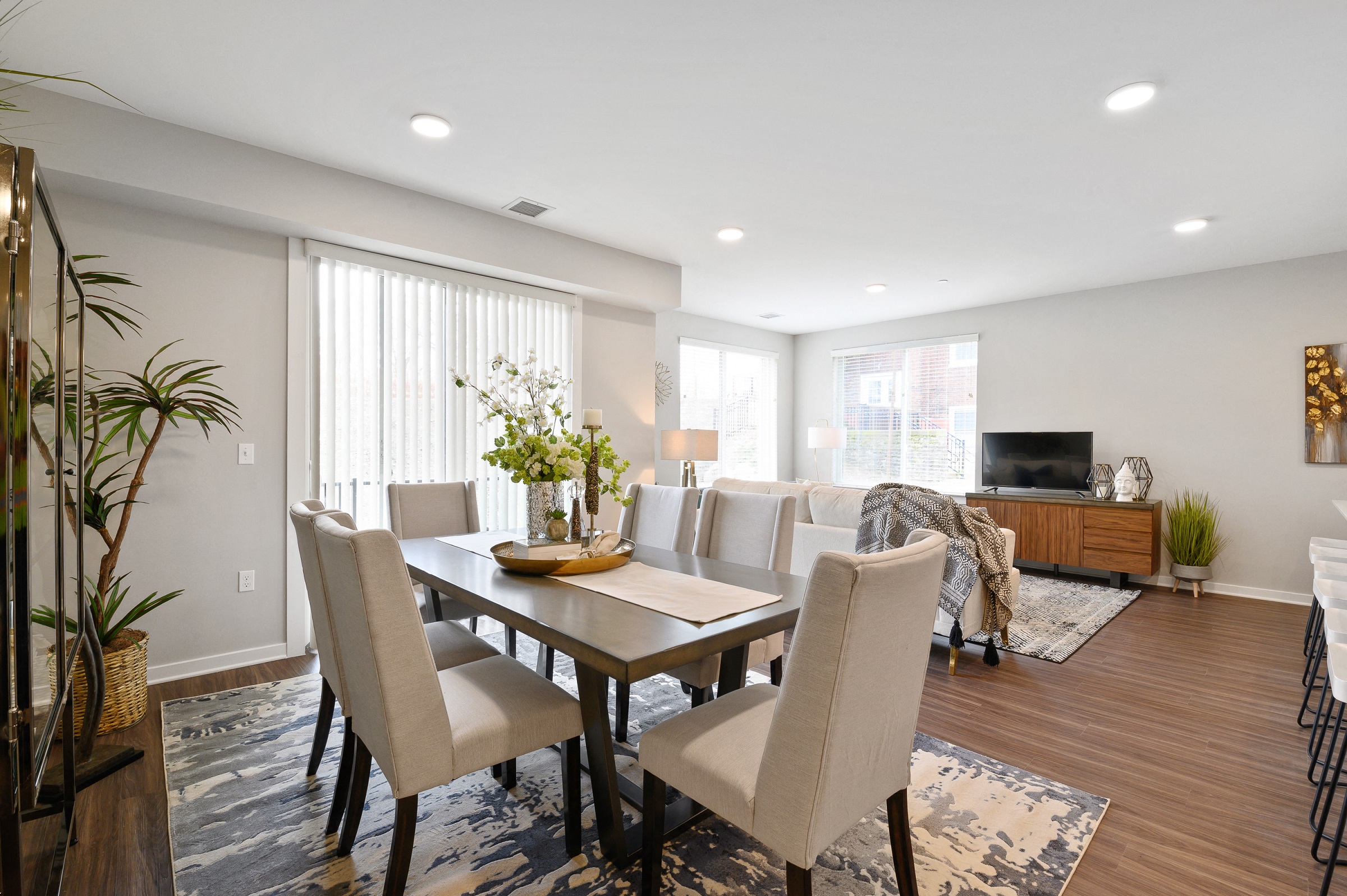 Large dining area with sunny windows, overhead lighting, and vinyl hardwood flooring