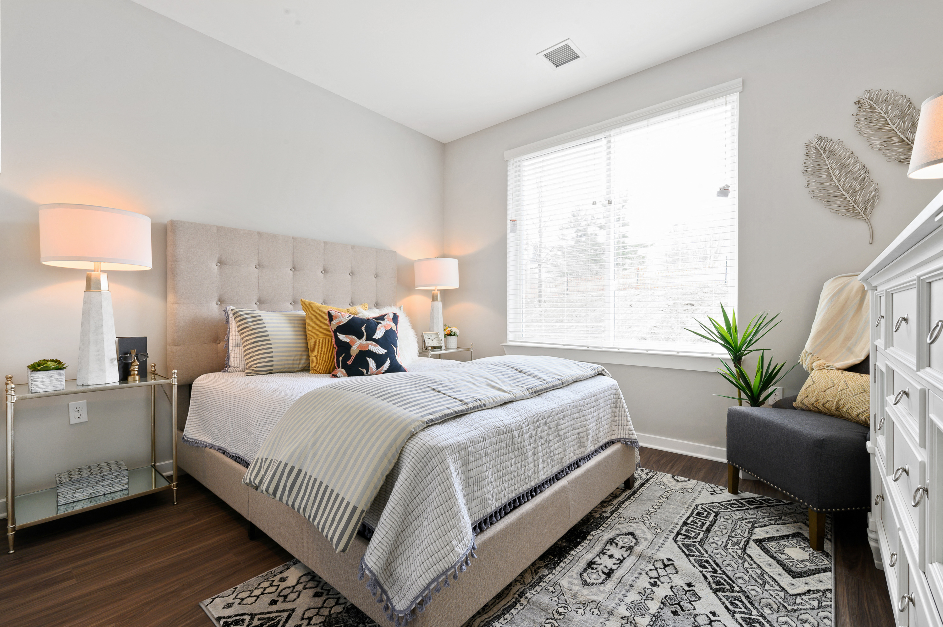 Spacious bedroom with large window and contemporary furnishings in neutral colors