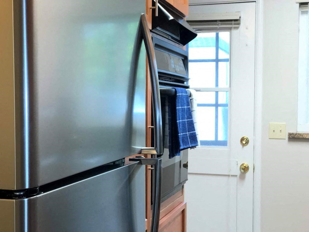 a stainless steel refrigerator in a kitchen with a window