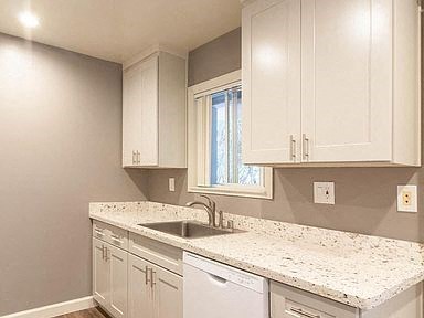a kitchen with white cabinets and a sink and a window