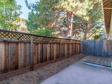 a backyard with a wooden fence and a concrete patio