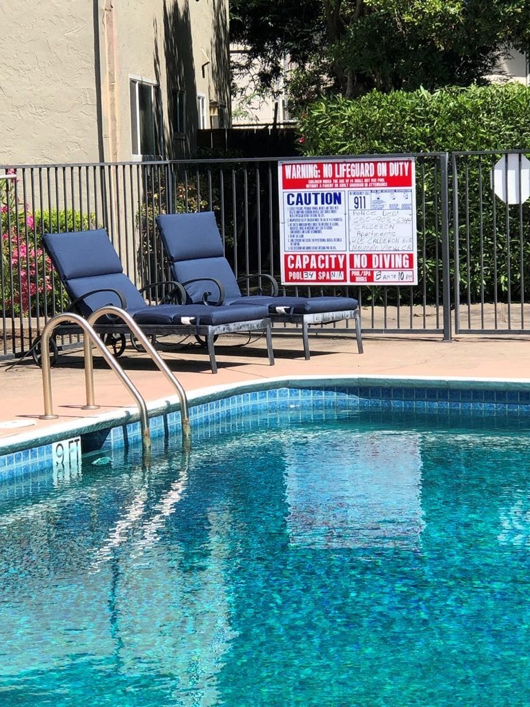 a swimming pool with two blue chairs next to it