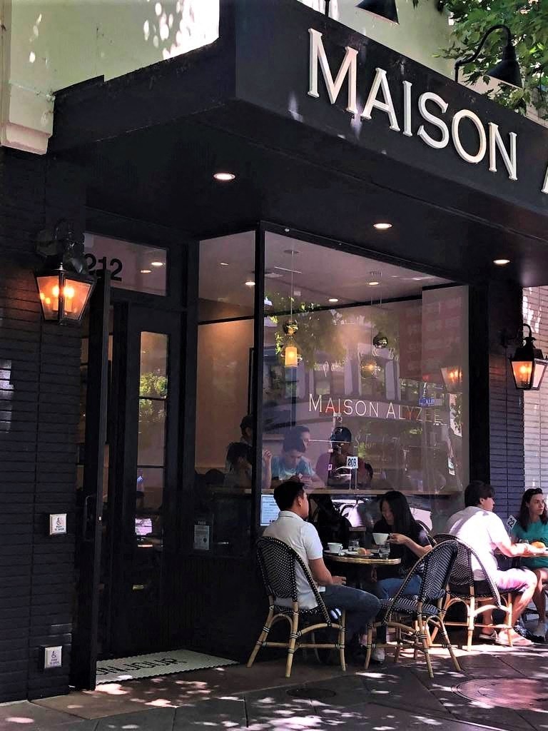 people are sitting at tables outside of a restaurant