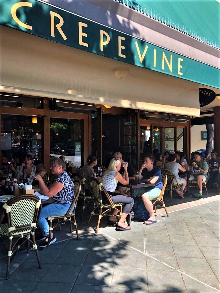 people sitting at tables outside of a restaurant
