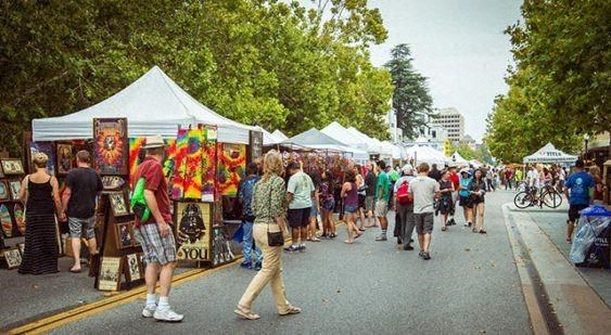 a crowd of people walking around a street market