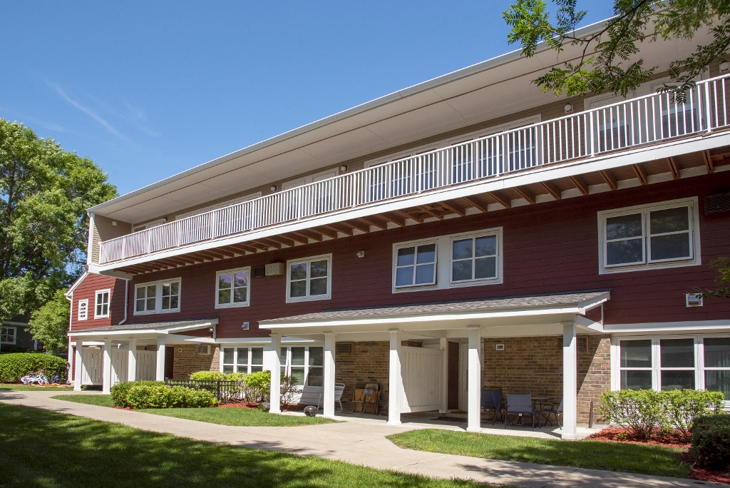 an exterior view of a red building with a balcony and a sidewalk