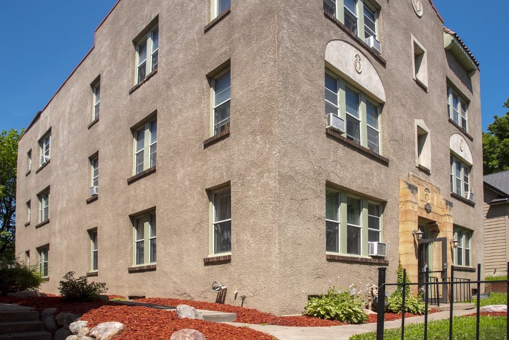 a large brick building with windows and a sidewalk in front of it