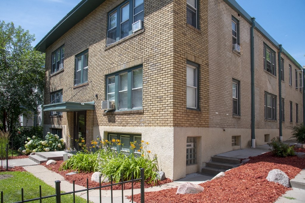 a brick apartment building with a garden in front of it