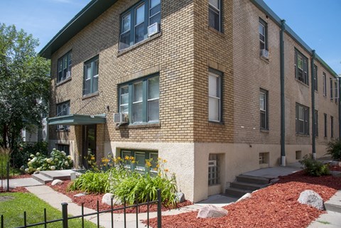 a brick apartment building with a garden in front of it