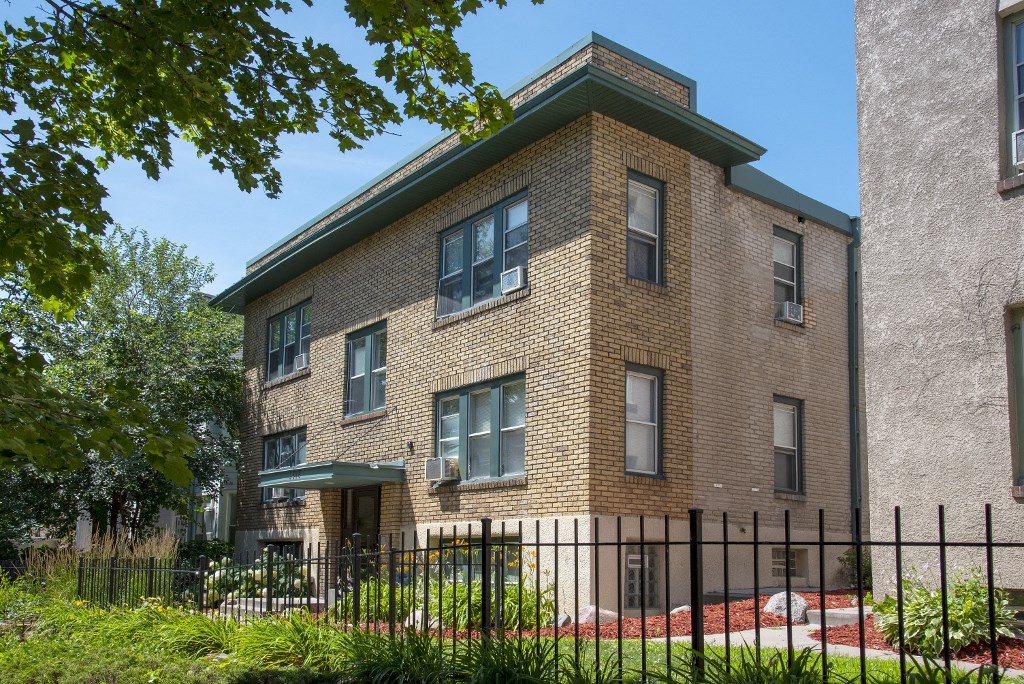 a brick apartment building with a fence in front of it