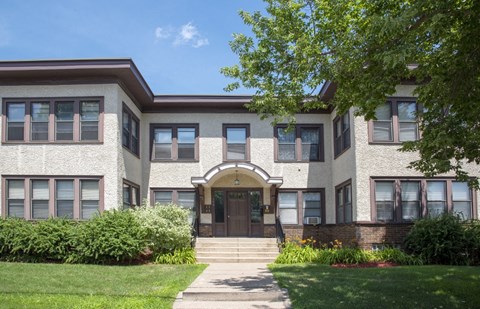 the front of a brick building with steps and a lawn
