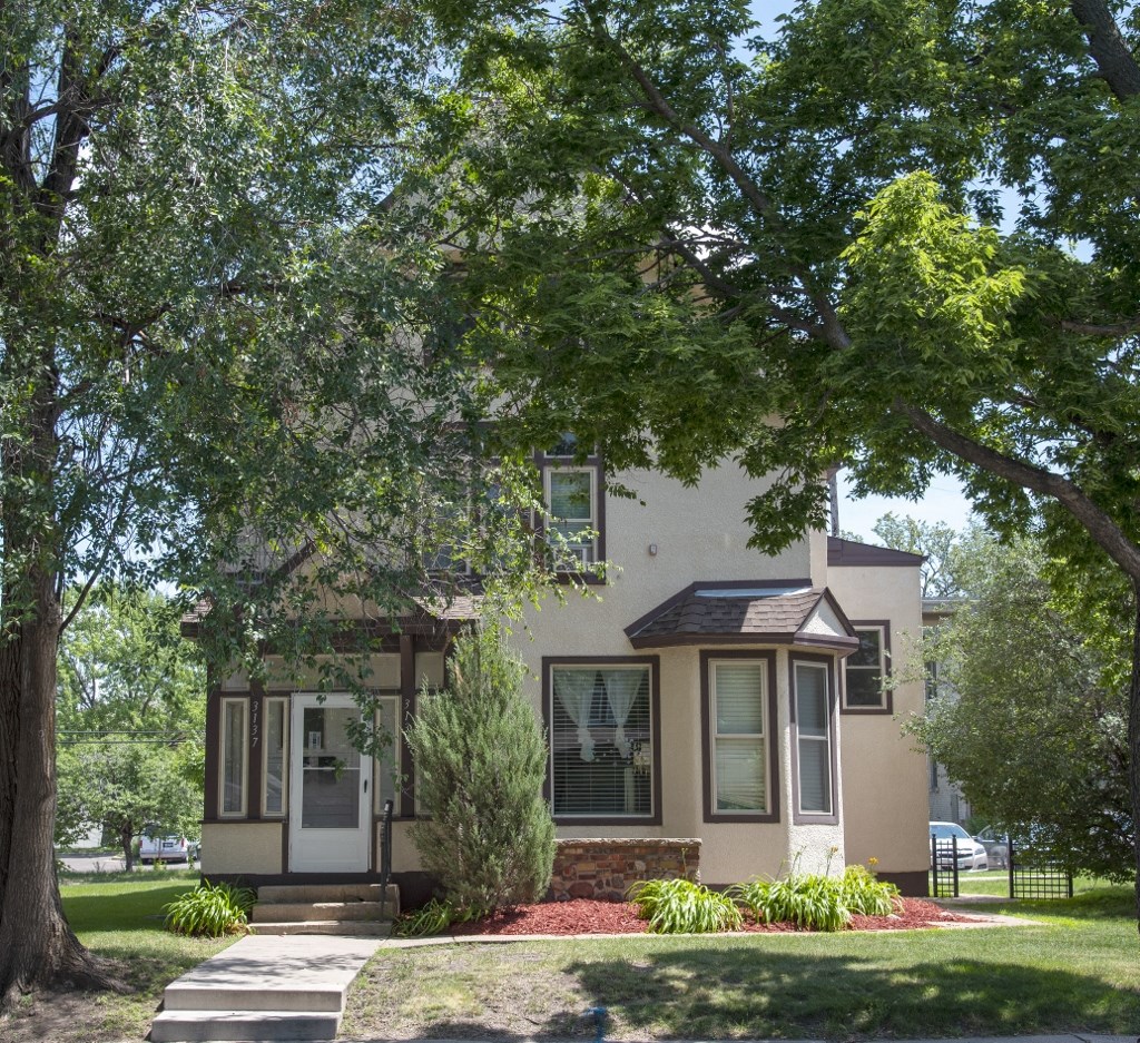 a house with a lawn and trees in front of it