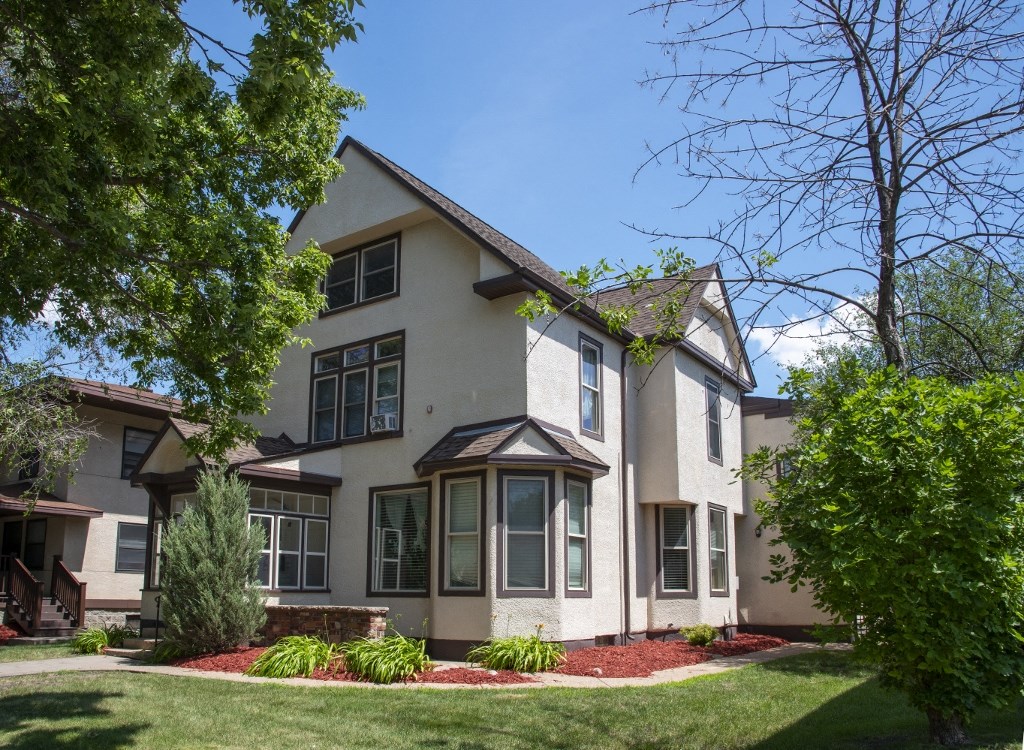 the front of a house with a lawn and trees