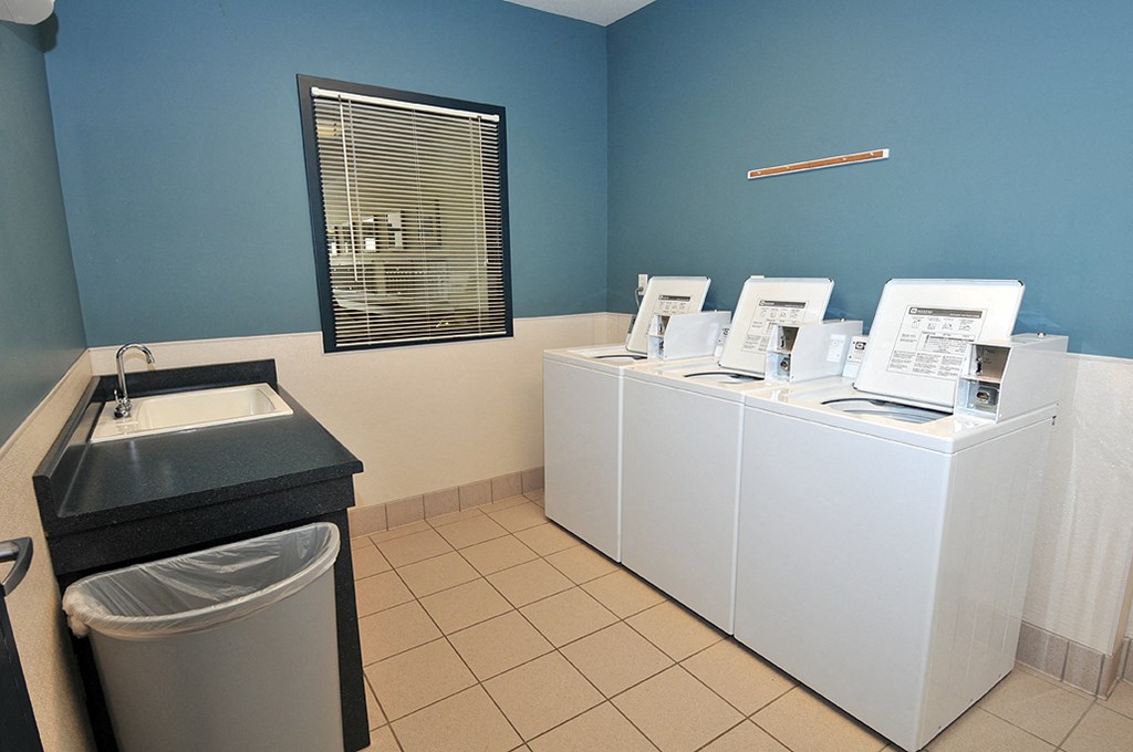 a laundry room with four washers and a sink and a washing machine